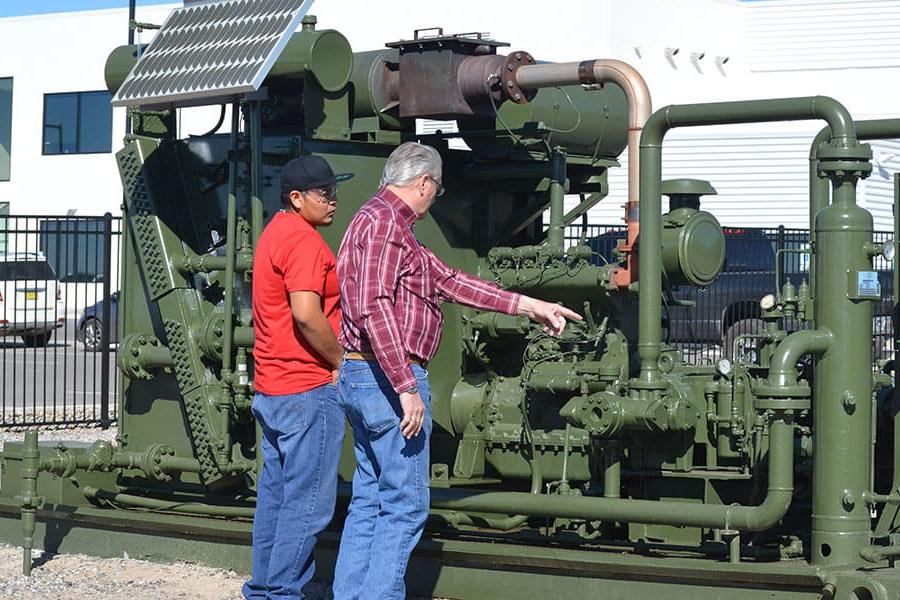 Two individuals look and point at natural gas valves in an outdoor setting