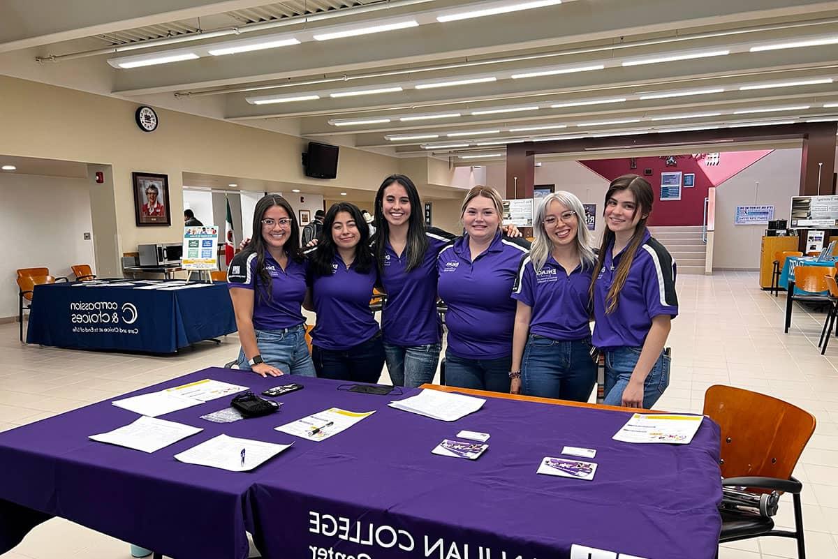 SJC Enlace Ambassadors standing in front of table.